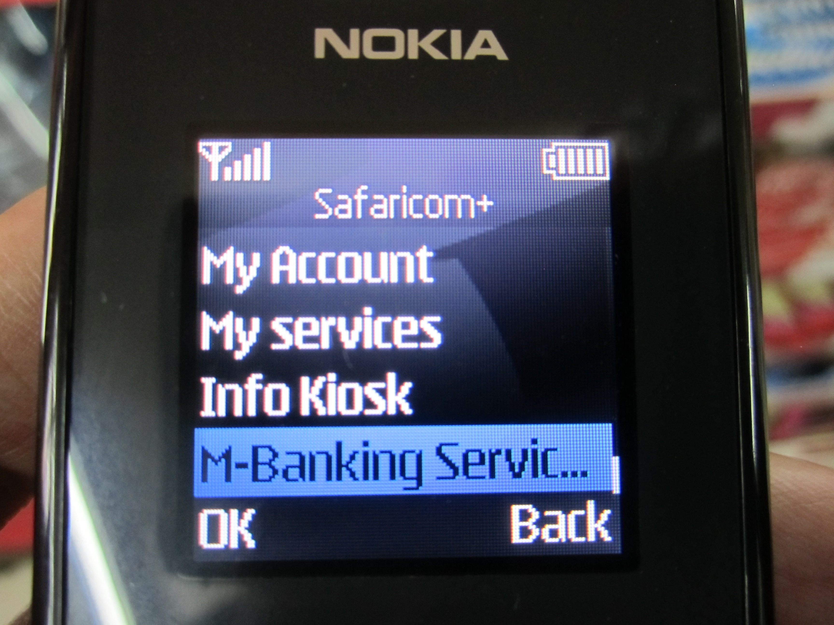Feature phone showing a mobile banking menu, illustrating the importance of USSD and accessible phone-led finance.